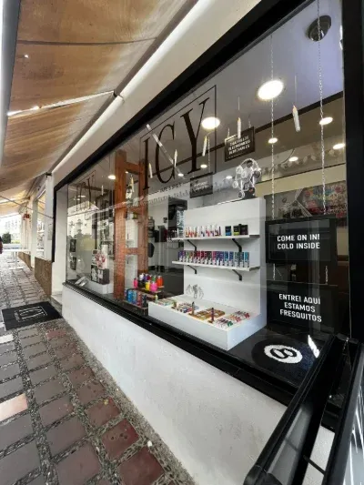 Shop window showcasing various vape products and flavors, including signs reading "COME ON IN! COLD INSIDE" and "ENTRE ADUI ESTAMOS FRESQUITOS."