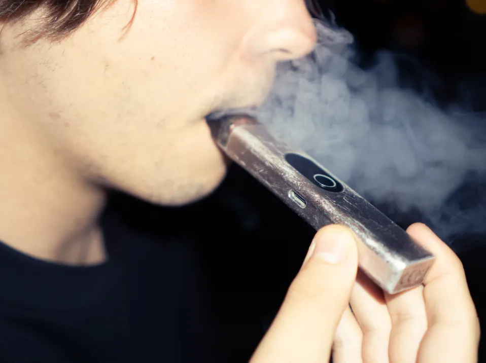 Persona utilizando un vape desechable emitiendo vapor.